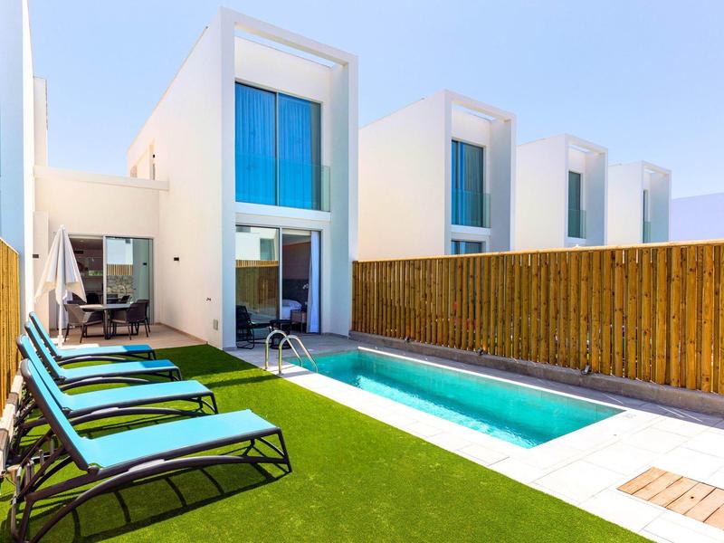 Nowoczesne białe domy wakacyjne z prywatnym basenem i leżakami na trawniku