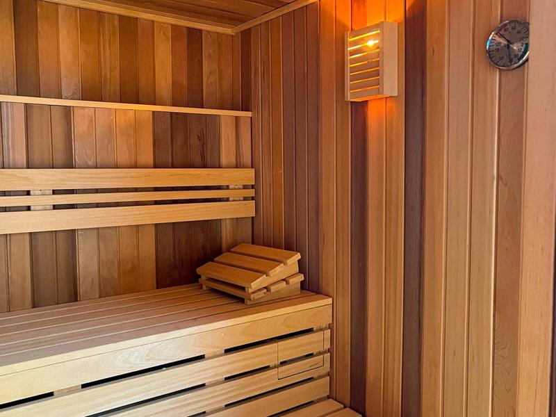 Wnętrze drewnianej sauny z ławkami, zagłówkami i ciepłym oświetleniem dla relaksu.