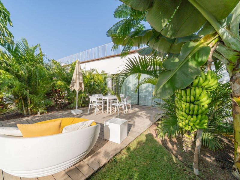 Przytulny taras z okrągłą sofą, miejscami do siedzenia i tropikalnymi roślinami.