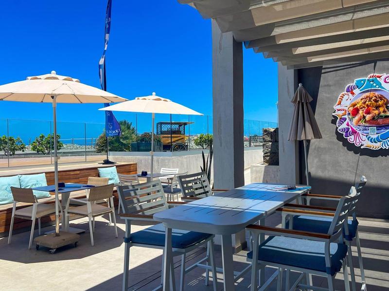Taras z stołami, krzesłami i parasolami pod czystym niebem, widok na morze
