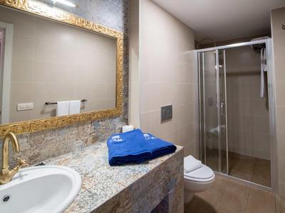 Modern bathroom with shower, granite countertop, and blue towel in hotel room.