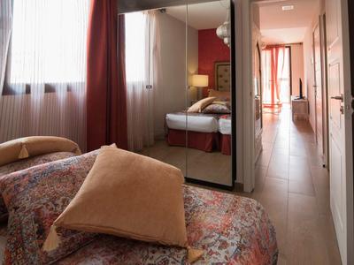 Cozy bedroom with floral bedspread, pillows, and large mirrors on closet doors.