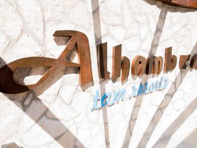 Metalllogo 'Alhambra' an weißer Steinwand mit Schatten