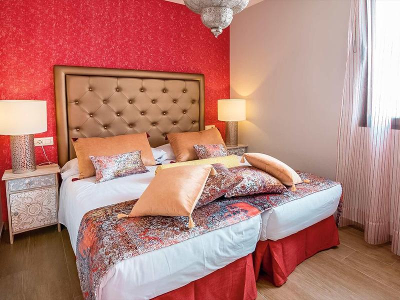 Cozy hotel room with two single beds, brown tufted headboard, and red accents.