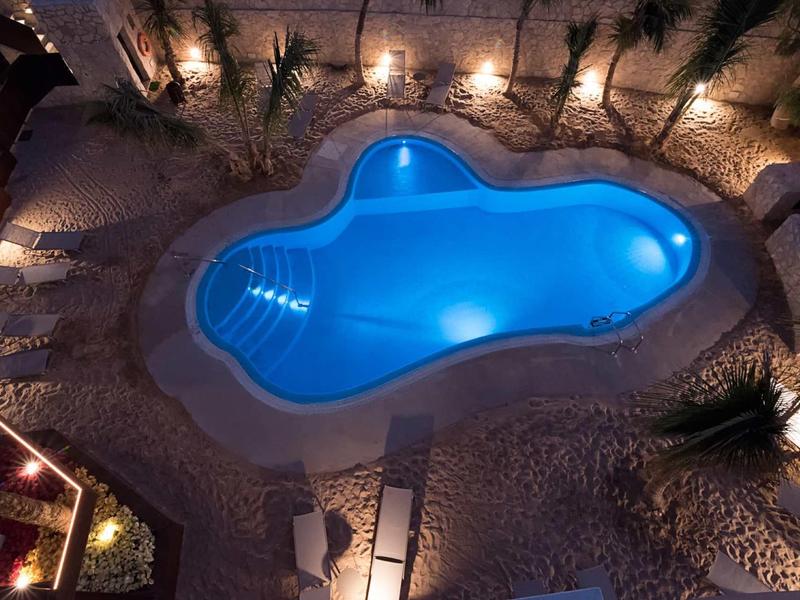 Night view of a lit pool with steps and surrounding terrace at a hotel.