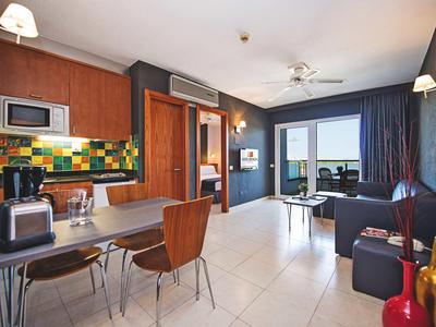 Modern furnished apartment with kitchen, dining area, and living room with balcony.