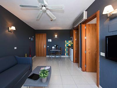 Modern furnished living room with sofa, fan, TV, and table in a holiday apartment.