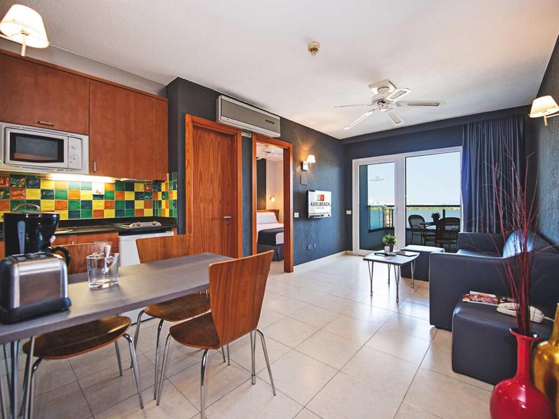 Modern furnished apartment with kitchen, dining area, and living room with balcony.