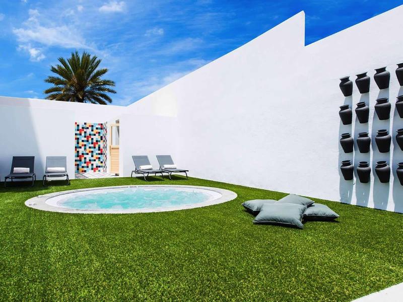 Modern outdoor area with small pool, lounge chairs, and green grass lawn.