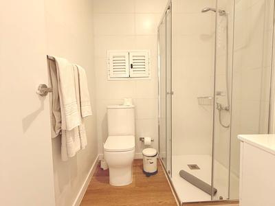 Nowoczesna łazienka z prysznicem, toaletą, ręcznikami i drewnianą podłogą.