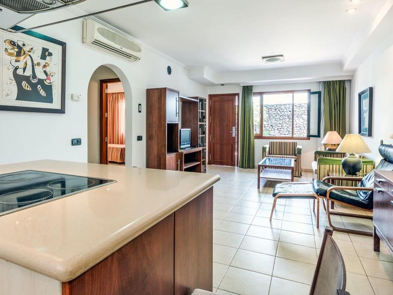 Jasny salon z otwartą kuchnią, jadalnią i dużymi oknami z widokiem na zieleń.