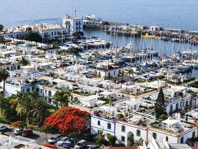 Hafen mit vielen Booten und weißen Gebäuden in einer Küstenstadt bei klarem Himmel.
