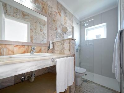 Badezimmer mit großem Spiegel, Marmorwaschbecken, Glasdusche und weißem Handtuch.