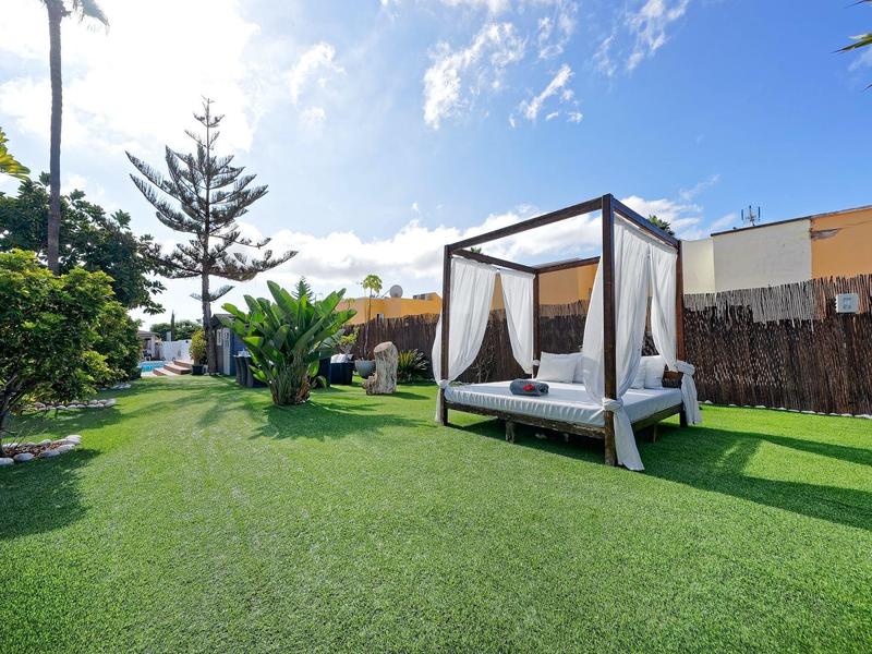 Grüner Garten mit Rasen, weißem Pavillon-Bett und blauem Himmel mit Wolken.