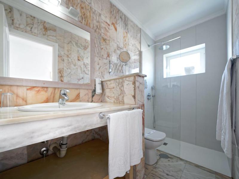 Badezimmer mit großem Spiegel, Marmorwaschbecken, Glasdusche und weißem Handtuch.