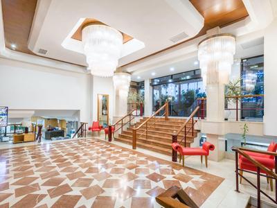 Ampia hall d'hotel con scale, pavimento lucido e lampadari moderni.