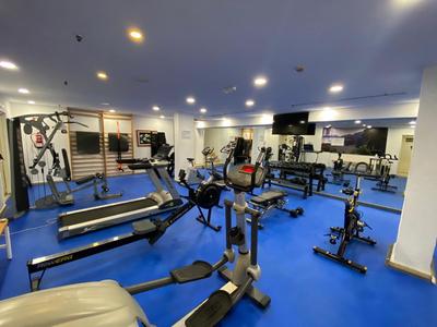 Palestra moderna con varie attrezzature per allenamento e grande specchio sulla parete.