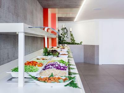 Buffet con insalate e verdure fresche in una stanza moderna e luminosa.