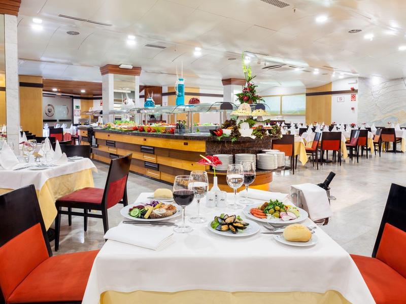 Ampio ristorante dell'hotel con tavoli apparecchiati e sedie rosse imbottite.