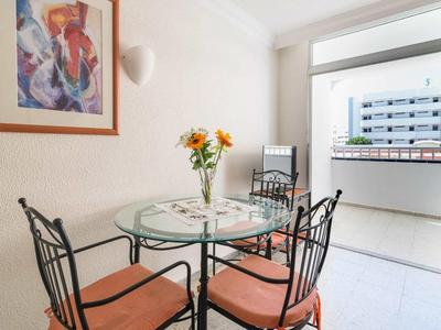 Moderní jídelní prostor se skleněným stolem a čtyřmi kovovými židlemi vedle hotelového balkonu.