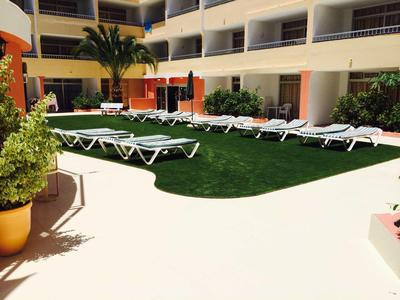 Cortile dell'hotel con lettini intorno a un prato verde e balconi circostanti.