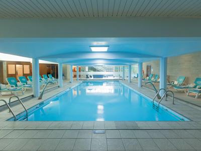 Kryty basen z leżakami i sztucznym oświetleniem w nowoczesnym hotelu.