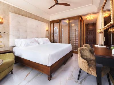 Elegancki pokój hotelowy z dużym łóżkiem, fotelem, biurkiem i drewnianymi ścianami.