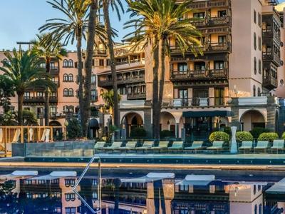 Spokojny hotelowy basen otoczony palmami i budynkami o zachodzie słońca.