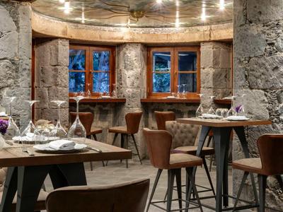 Stylowa jadalnia z kamiennymi ścianami i nakrytymi stołami.