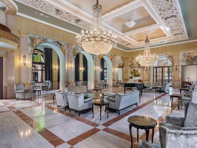 Elegancka sala z szarymi sofami, żyrandolami i marmurową podłogą.