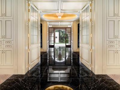 Elegancki korytarz hotelowy z czarną marmurową podłogą i wbudowanymi białymi szafami.