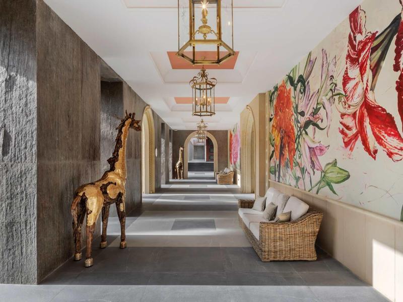 Korytarz z dekoracją żyrafy i kolorową ścianą kwiatową w nowoczesnym hotelu.