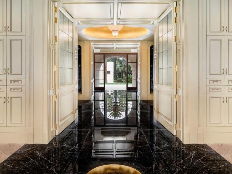 Elegancki korytarz hotelowy z czarną marmurową podłogą i wbudowanymi białymi szafami.