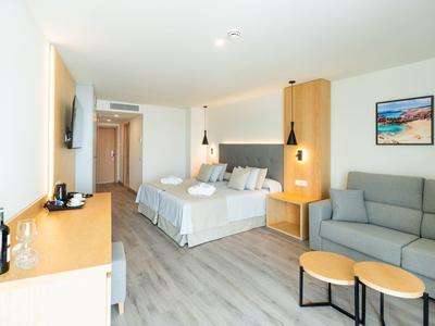 Modern hotelkamer met tweepersoonsbed, bank en kleine tafel.
