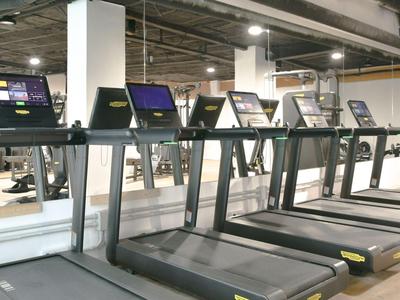 Moderne fitnessruimte met meerdere loopbanden in een lichte hal.