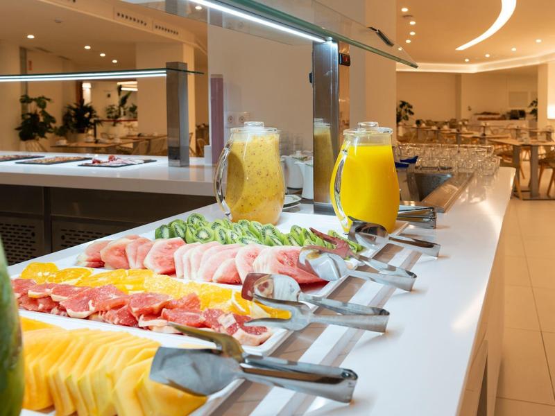 Buffet met vers fruit, vleeswaren en sappen in een modern restaurant.