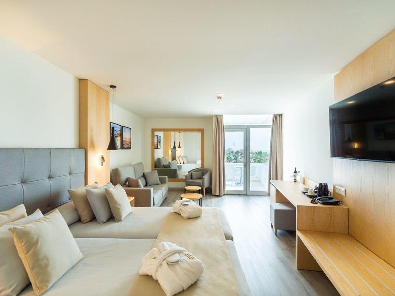 Moderne hotelkamer met twee bedden, tv en balkon met uitzicht.