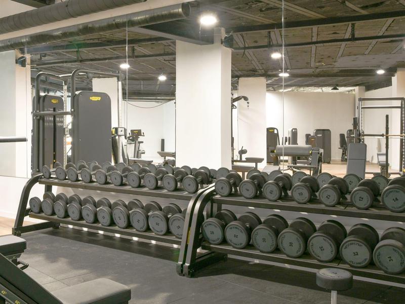 Modern fitnesscentrum met halters en krachtapparatuur in een lichte ruimte.