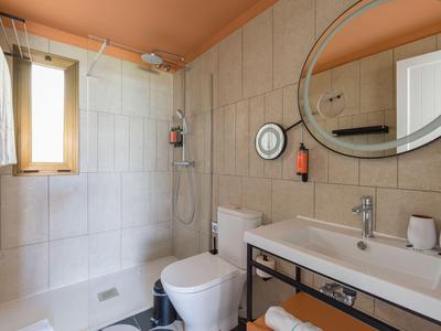 Modern bathroom with shower, toilet, sink, and large mirror in neutral tones.