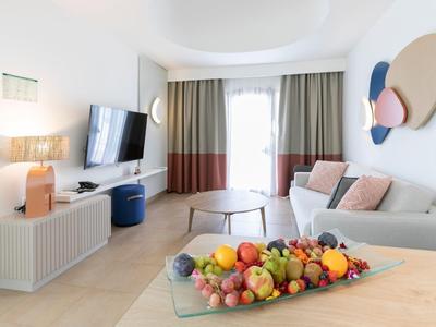 Modern living area with sofa, decorative wall art, and table with fruit in a hotel room.