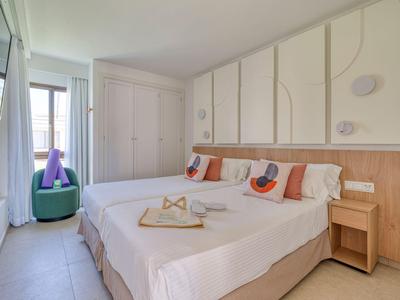Modern hotel room with two single beds, decorative pillows, and a balcony.