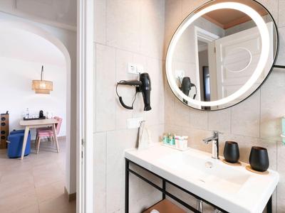 Modern bathroom with round illuminated mirror and hairdryer in a hotel room.