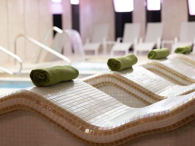 Spa loungers with green towels in a modern wellness area.
