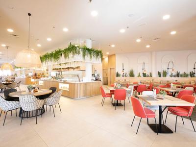 Bright restaurant with modern furniture and green plants in the decor.