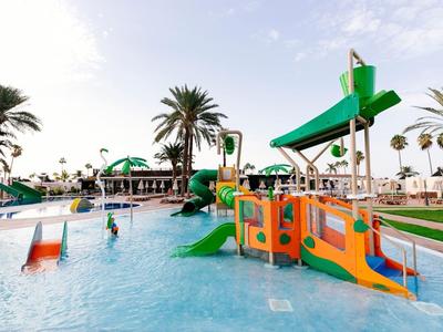 Water park with colorful slides and palm trees for families at a hotel resort.