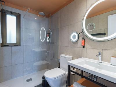 Modern bathroom with walk-in shower, toilet, and illuminated mirror.