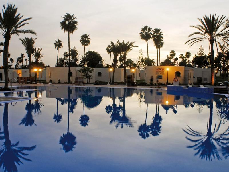 Pool with palm trees at sunset in a resort