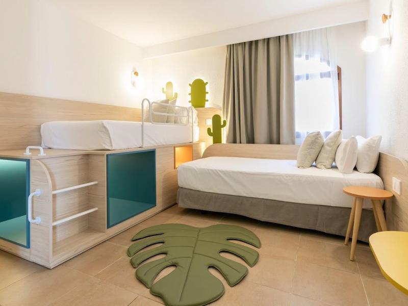 Modern hotel room with double bed, wood accents, and green leaf rug.