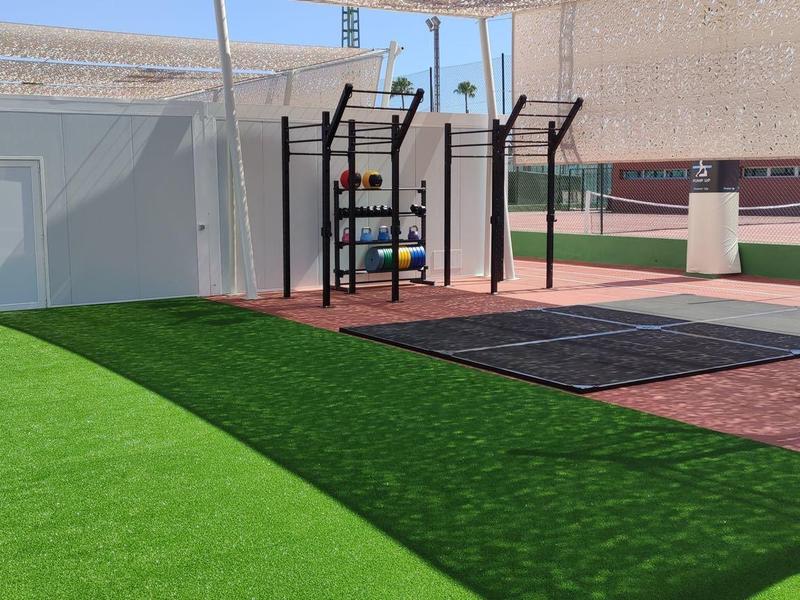 Modern outdoor fitness area with artificial grass and various workout equipment.