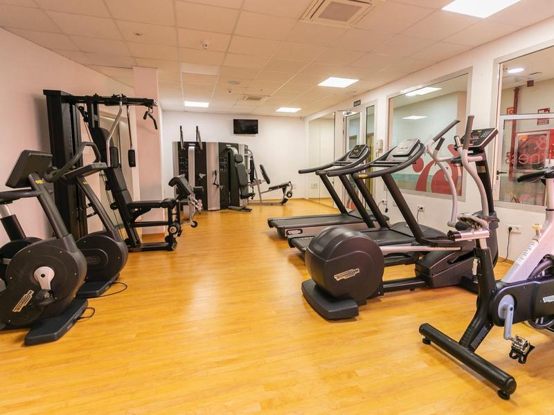 Gym with treadmills, cross trainers, and other exercise equipment on wooden floor.